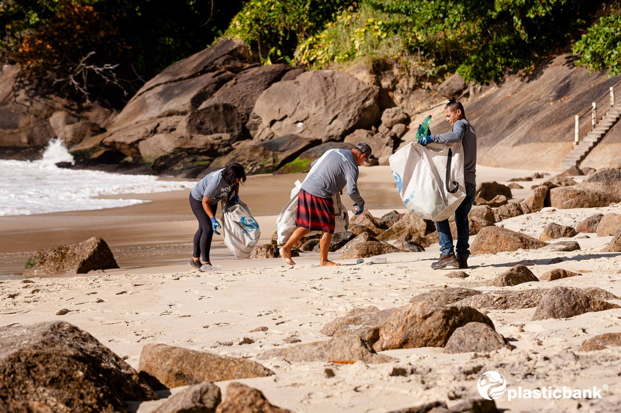 a number of people collecting waste plastic on a beach
